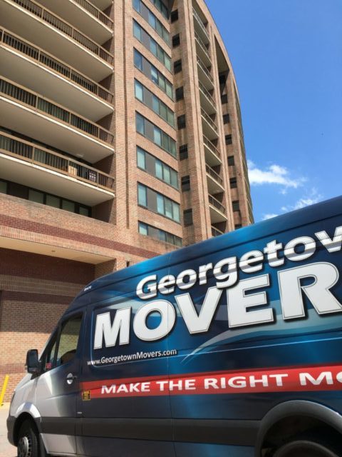 Georgetown Moving and Storage van parked in front of large apartment complex.