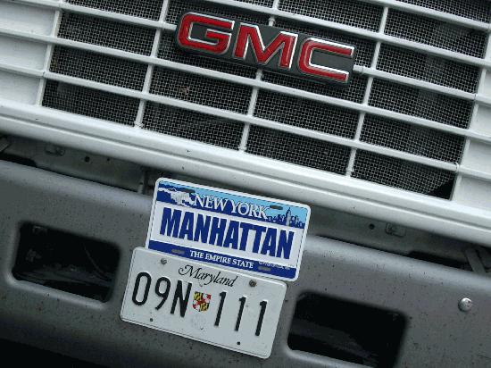 Close-up of front grille of GMC truck with Maryland and New York license plates. NY plate says "MANHATTAN"