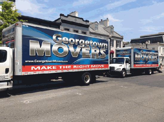 Georgetown Moving and Storage Company trucks parked on the side of a road in front of a house.