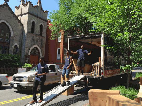 Georgetown Moving and Storage movers walking out of the back of a moving truck, unloading boxes.