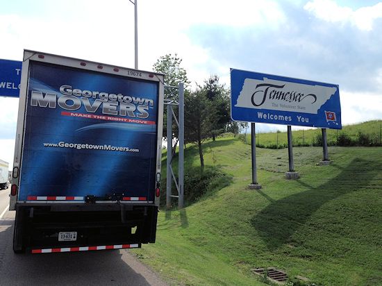 Georgetown Moving and Storage truck passing Welcome To Tennessee sign on highway.