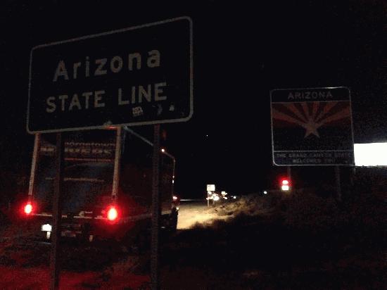 Arizona State Line highway sign at night, with Georgetown Moving and Storage truck driving past.