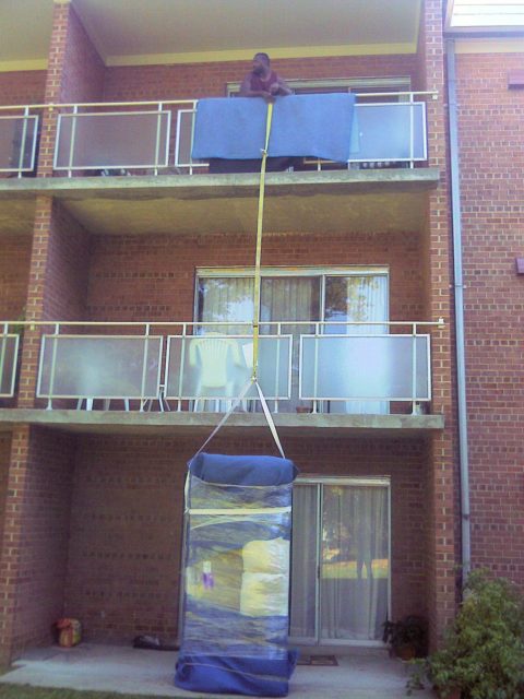 movers hoisting furniture over a balcony
